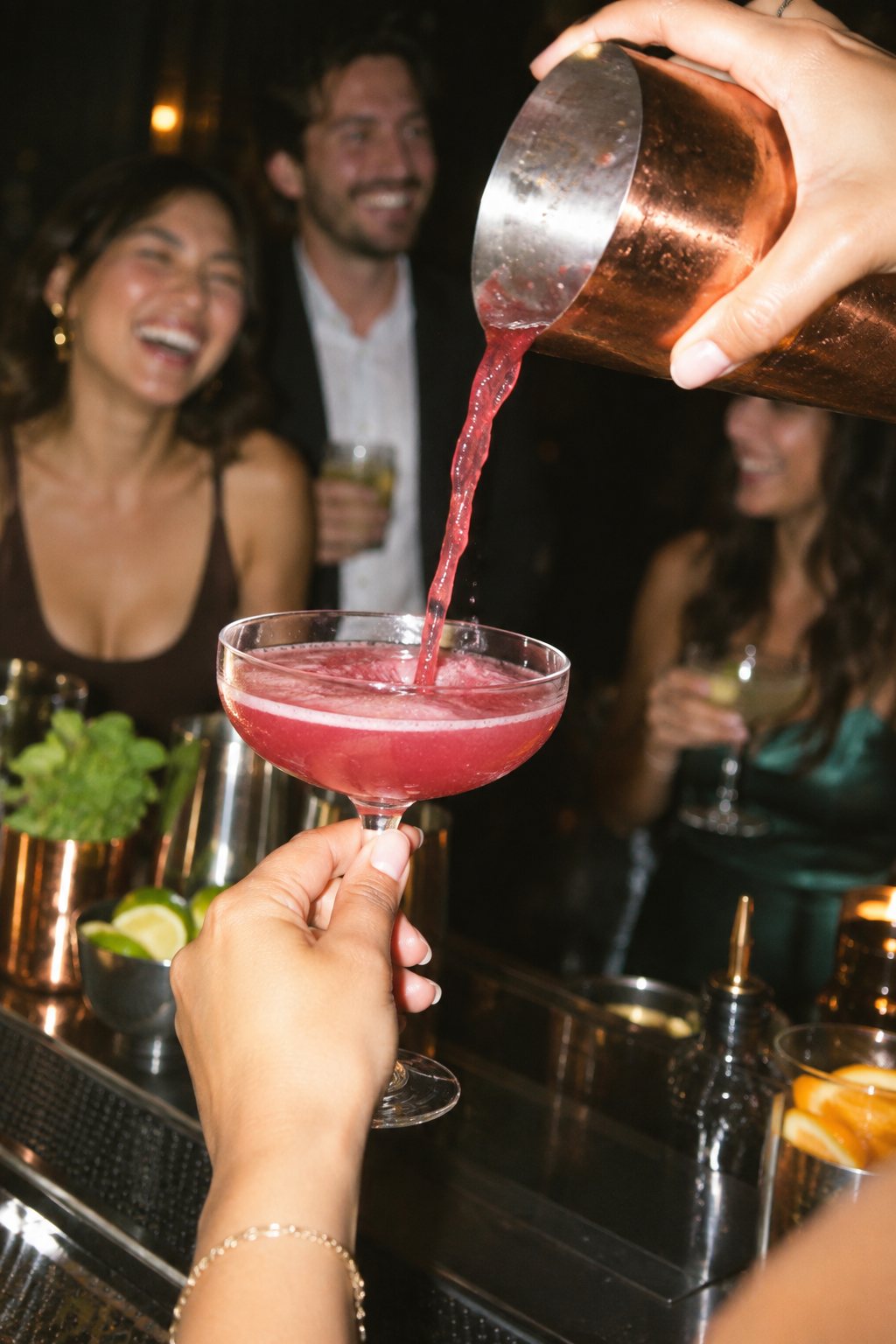 Bartender pouring a berry-pink cocktail into a coupe glass at a mobile bar
